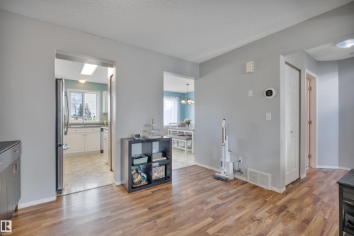 Warm wood-finish flooring extending through the primary room - 102 4415 South Park Drive, Leduc, AB - Indoor Photo Showing Other Room