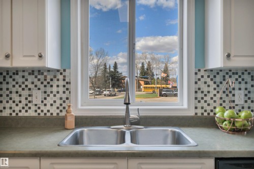 Kitchen sink with a dual basin, a stainless steel faucet, and a window with white trim - 102 4415 South Park Drive, Leduc, AB - Indoor Photo Showing Kitchen With Double Sink