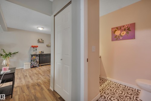Wood-finish flooring throughout the main area and a built-in cabinet with floating shelves - 102 4415 South Park Drive, Leduc, AB - Indoor Photo Showing Other Room
