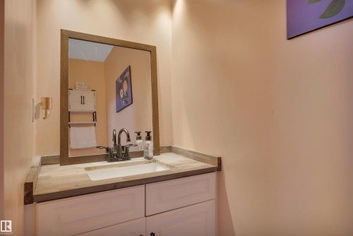 Bathroom vanity featuring a wood-finish countertop, integrated sink, and dark bronze faucet - 102 4415 South Park Drive, Leduc, AB - Indoor Photo Showing Bathroom
