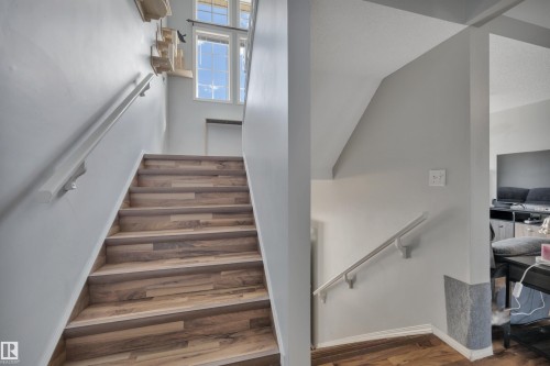 Staircase featuring wood-finish flooring, white risers, and a white handrail - 102 4415 South Park Drive, Leduc, AB - Indoor Photo Showing Other Room