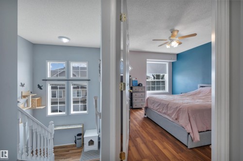 Upper-level hallway with a staircase featuring white balusters and a light wood-finish flooring - 102 4415 South Park Drive, Leduc, AB - Indoor Photo Showing Bedroom