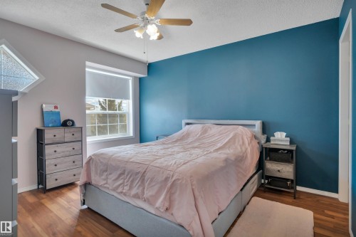 Bedroom featuring a prominent accent wall and wood-finish flooring - 102 4415 South Park Drive, Leduc, AB - Indoor Photo Showing Bedroom