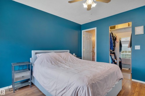 Room featuring wood-finish flooring, a ceiling fan with integrated lighting, and a walk-in closet with built-in shelving - 102 4415 South Park Drive, Leduc, AB - Indoor Photo Showing Bedroom
