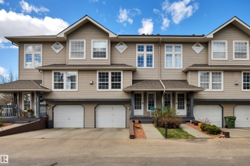 Multi-level townhouse exterior featuring beige horizontal siding and white-framed windows - 102 4415 South Park Drive, Leduc, AB - Outdoor With Facade