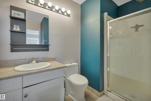 Bathroom featuring a glass-enclosed shower, white vanity with an oval basin, light-toned countertop, and tiled flooring - 102 4415 South Park Drive, Leduc, AB - Indoor Photo Showing Bathroom