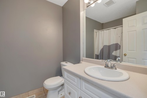 Bathroom featuring a white vanity with an integrated sink, a large wall-mounted mirror, and overhead vanity lighting - 102 4415 South Park Drive, Leduc, AB - Indoor Photo Showing Bathroom