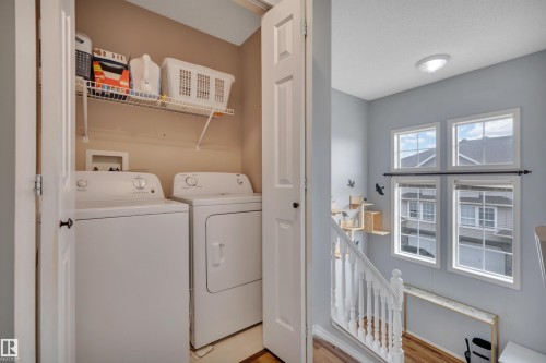 Dedicated laundry closet featuring a white washer and dryer pair, with a wire shelf above for storage - 102 4415 South Park Drive, Leduc, AB - Indoor Photo Showing Laundry Room