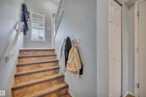 Interior staircase featuring wood-finish treads with dark trim, a white painted handrail, and light blue wall paint - 102 4415 South Park Drive, Leduc, AB - Indoor Photo Showing Other Room