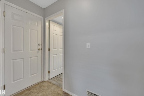Entryway featuring a paneled door with brushed nickel hardware, light gray walls, and wood-finish flooring - 102 4415 South Park Drive, Leduc, AB - Indoor Photo Showing Other Room