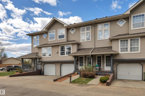 Townhouse exterior featuring light-colored siding and multiple large windows - 102 4415 South Park Drive, Leduc, AB - Outdoor With Facade
