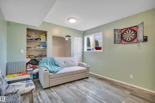 Room featuring wood-finish flooring, a double window, wall shelving, a built-in alcove, and an overhead light fixture - 102 4415 South Park Drive, Leduc, AB - Indoor