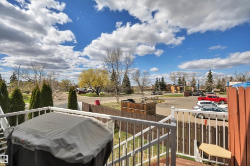 Wood-finish deck with white railing, overlooking mature trees and open space - 102 4415 South Park Drive, Leduc, AB - Outdoor With View