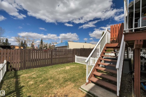 Expansive backyard featuring a manicured lawn, full privacy fencing, and a white picket fence accent - 102 4415 South Park Drive, Leduc, AB - Outdoor