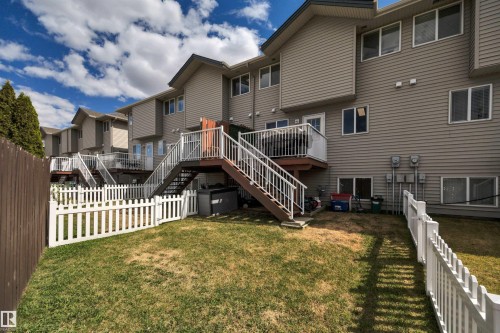 Manicured lawn area featuring a white picket fence and a privacy fence - 102 4415 South Park Drive, Leduc, AB - Outdoor With Deck Patio Veranda With Exterior