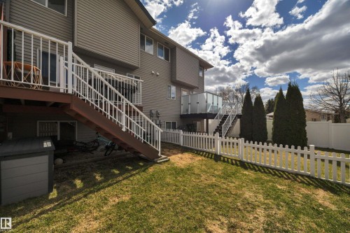 Exterior featuring tan siding, a multi-level deck with white railings, and a glass-paneled balcony - 102 4415 South Park Drive, Leduc, AB - Outdoor
