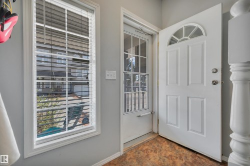 Entryway featuring a paneled door with an arched transom window, wood-finish flooring, a full-length window with blinds, and light gray wall paint - 102 4415 South Park Drive, Leduc, AB - Indoor Photo Showing Other Room