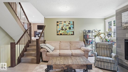 Living area featuring wood-finish flooring, a contemporary fireplace with a tiled surround, crown molding, and recessed lighting - 27 Addison Crescent, St. Albert, AB - Indoor Photo Showing Living Room With Fireplace