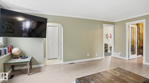 Expansive room featuring wood-finish flooring, light green walls, and white crown molding - 27 Addison Crescent, St. Albert, AB - Indoor