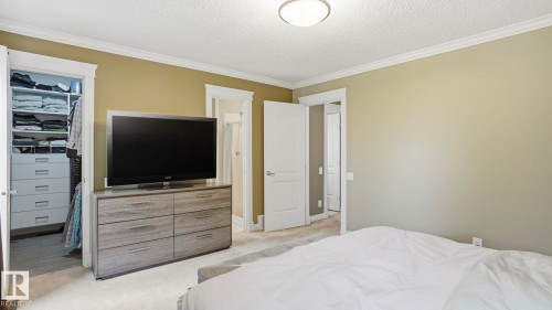 Room featuring a built-in closet system with shelving and drawers, neutral wall paint, white trim, and a ceiling light fixture - 27 Addison Crescent, St. Albert, AB - Indoor Photo Showing Bedroom