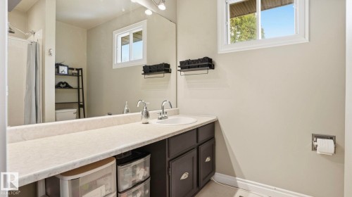 Bathroom vanity featuring an integrated sink, dark wood cabinetry, and a large mirror - 27 Addison Crescent, St. Albert, AB - Indoor Photo Showing Bathroom