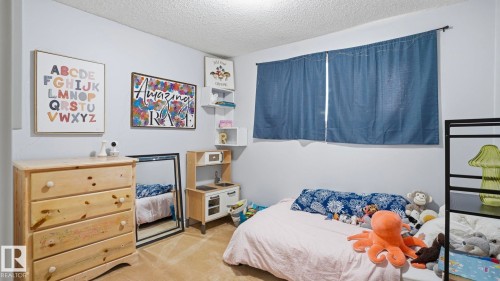 Neutral wall colors, textured ceiling, a window with curtains, and carpeting define this space - 27 Addison Crescent, St. Albert, AB - Indoor Photo Showing Bedroom