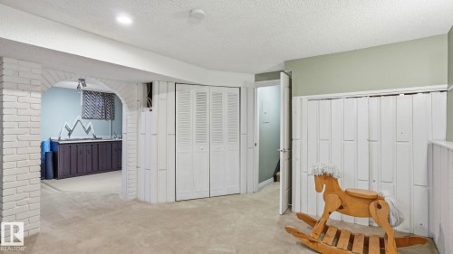 Carpeted room featuring white shiplap paneling and an arched brick doorway - 27 Addison Crescent, St. Albert, AB - Indoor
