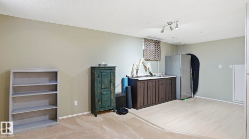 Recreational space featuring a built-in wet bar with dark wood cabinetry and a stainless steel sink - 27 Addison Crescent, St. Albert, AB - Indoor Photo Showing Other Room
