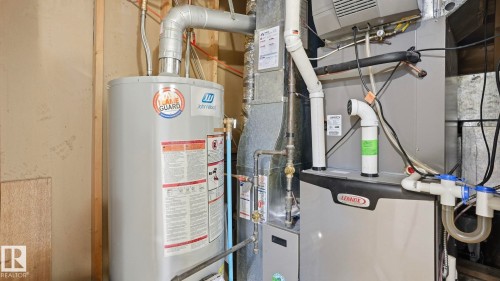 Utility room featuring a John Wood hot water heater, Lennox furnace, and extensive ductwork - 27 Addison Crescent, St. Albert, AB - Indoor Photo Showing Basement