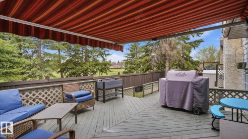 Outdoor deck space featuring a retractable striped awning, wood-finish flooring, and lattice railing - 27 Addison Crescent, St. Albert, AB - Outdoor With Deck Patio Veranda With Exterior