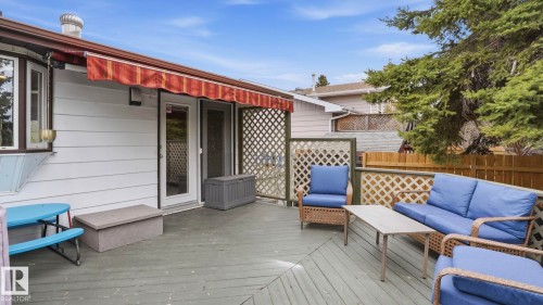 Expansive outdoor deck featuring wood-finish flooring, a white siding exterior, and a red and white striped awning - 27 Addison Crescent, St. Albert, AB - Outdoor With Deck Patio Veranda With Exterior