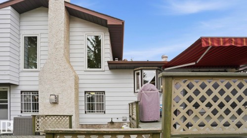 Wood-decked patio with a retractable awning, featuring a textured stucco chimney and bay windows - 27 Addison Crescent, St. Albert, AB - Outdoor With Exterior