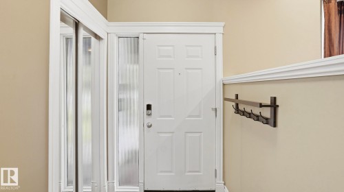 Entryway featuring a paneled door with a frosted sidelight, a coat rack, and mirrored closet doors - 27 Addison Crescent, St. Albert, AB - Indoor Photo Showing Other Room