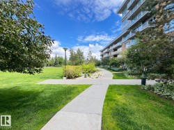 Expansive green space featuring a concrete pathway system, manicured lawns, mature trees, and surrounding landscaping elements - 