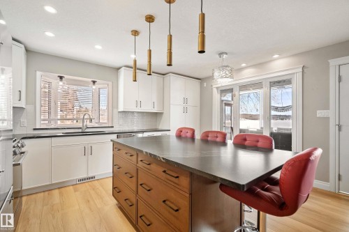 Contemporary kitchen featuring a large central island, white shaker-style cabinetry, and light wood-finish flooring - 104 Bayview Drive, Rural Parkland County, AB - Indoor