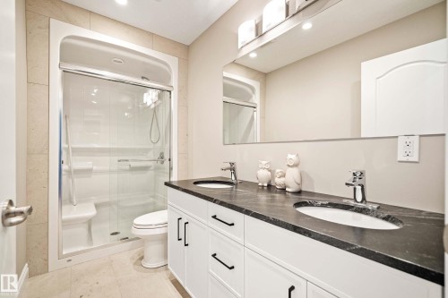 Bathroom featuring a dual vanity with a dark stone countertop, undermount sinks, and chrome faucets - 104 Bayview Drive, Rural Parkland County, AB - Indoor Photo Showing Bathroom