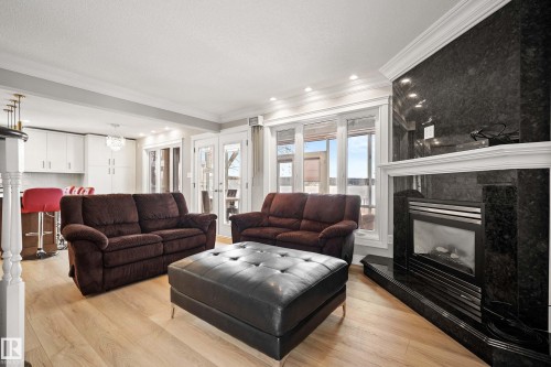 Living area featuring a black stone fireplace with a white mantel, light wood-finish flooring, and crown molding - 104 Bayview Drive, Rural Parkland County, AB - Indoor Photo Showing Living Room With Fireplace