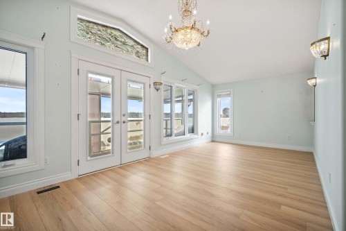 Spacious room featuring light wood-finish flooring, a vaulted ceiling, and multiple windows offering ample natural light - 104 Bayview Drive, Rural Parkland County, AB - Indoor
