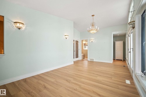 Spacious interior featuring wood-finish flooring, a crystal chandelier, and multiple wall sconces - 104 Bayview Drive, Rural Parkland County, AB - Indoor Photo Showing Other Room
