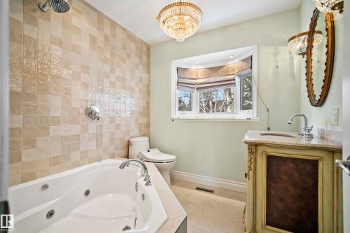 Bathroom featuring a jetted soaking tub, tiled shower surround, ornate vanity with a stone countertop, and a bay window with blinds - 104 Bayview Drive, Rural Parkland County, AB - Indoor Photo Showing Bathroom