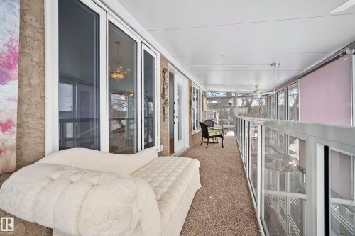 Enclosed upper-level balcony featuring full-height windows, a glass-paneled railing, and a textured ceiling with ceiling fans - 104 Bayview Drive, Rural Parkland County, AB - Indoor Photo Showing Other Room