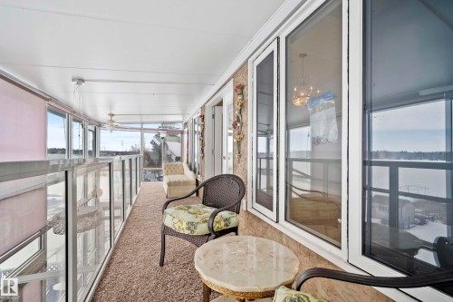 Enclosed sunroom featuring extensive glazing, textured wall finishes, and a neutral carpeted floor - 104 Bayview Drive, Rural Parkland County, AB -  With Balcony With Exterior