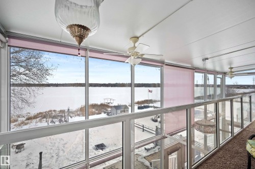 Enclosed balcony featuring floor-to-ceiling windows, glass railings, multiple ceiling fans, and a light-colored ceiling - 104 Bayview Drive, Rural Parkland County, AB - Indoor Photo Showing Other Room