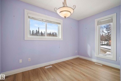 Interior room with light wood-finish flooring, white baseboards, and two windows providing natural light - 104 Bayview Drive, Rural Parkland County, AB - Indoor Photo Showing Other Room