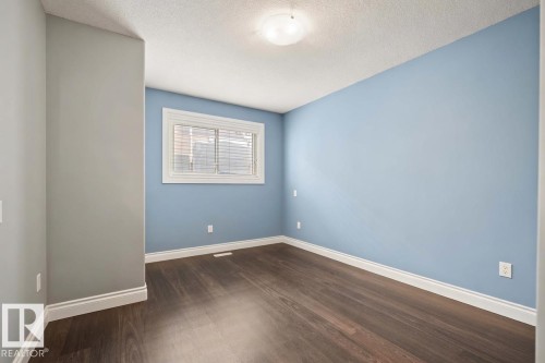 Spacious room featuring wood-finish flooring, light blue and grey wall paint, white baseboards, and a window with blinds - 104 Bayview Drive, Rural Parkland County, AB - Indoor Photo Showing Other Room