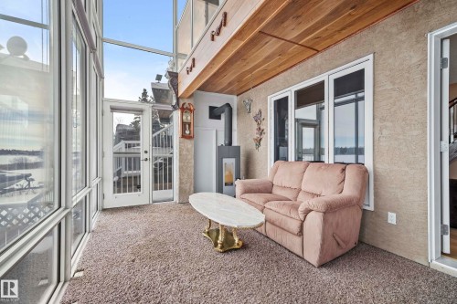Enclosed sunroom featuring expansive fenestration, wood plank ceiling, and a modern freestanding fireplace - 104 Bayview Drive, Rural Parkland County, AB -  Photo Showing Other Room