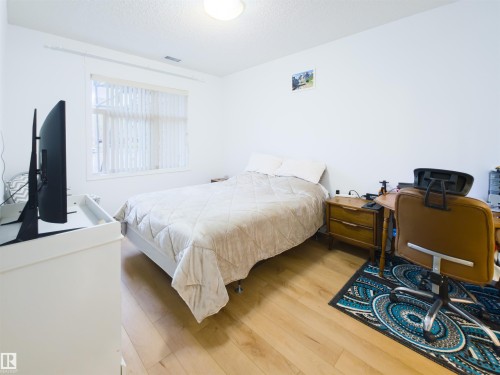 Bright interior room featuring wood-finish flooring, white walls, and a window with vertical blinds - 135 7825 71 Street, Edmonton, AB - Indoor Photo Showing Bedroom