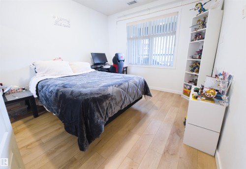 Bedroom featuring wood-finish flooring, white baseboards, and a window with vertical blinds - 135 7825 71 Street, Edmonton, AB - Indoor Photo Showing Bedroom