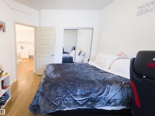 Bedroom featuring wood-finish flooring, white walls, and a five-panel interior door - 135 7825 71 Street, Edmonton, AB - Indoor Photo Showing Bedroom