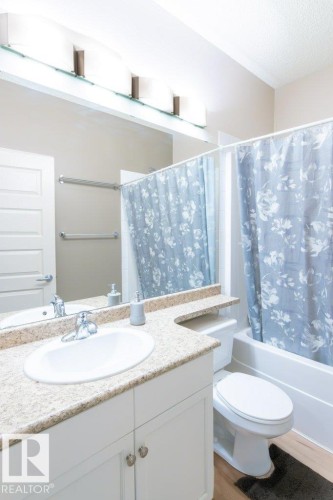 Bathroom vanity with white cabinetry, a speckled countertop, and an undermount sink - 135 7825 71 Street, Edmonton, AB - Indoor Photo Showing Bathroom